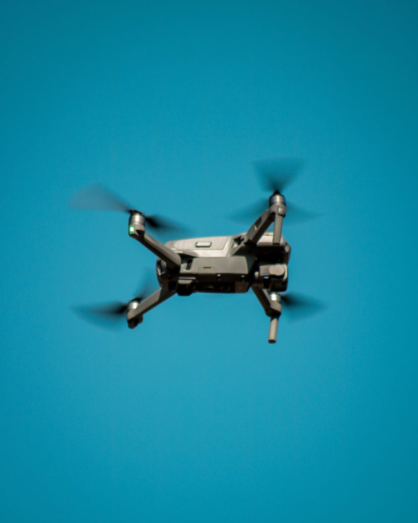 A modern drone flying against a clear blue sky, showcasing aviation technology.